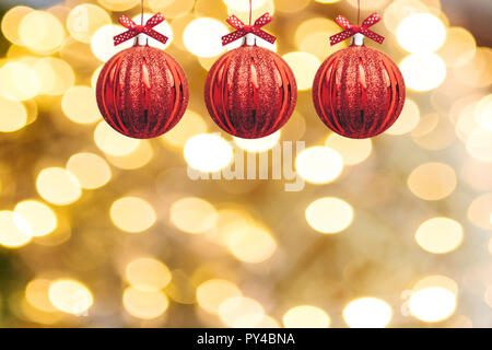 Festliche rote Kugeln oder Weihnachtsschmuck hängen in einer Reihe auf einem hellen Weihnachten Goldener Hintergrund Stockfoto