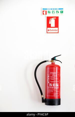 Rote Feuerlöscher an der Wand mit Warnungen montiert. Stockfoto