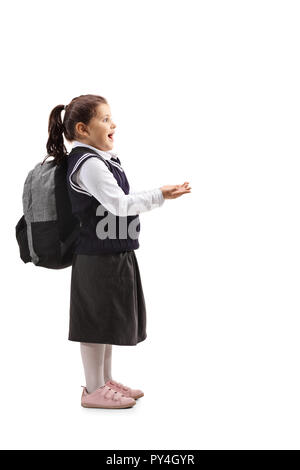 Volle Länge Profil Schuß eines überrascht Kleines Mädchen in Schuluniform ihre Hände, die vor ihr auf weißem Hintergrund Stockfoto