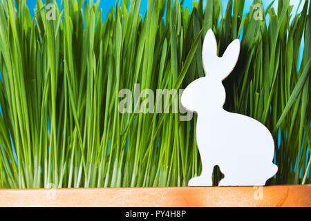 Osterhasen aus Holz Figur im Gras sitzen. Frühling Konzept. Stockfoto