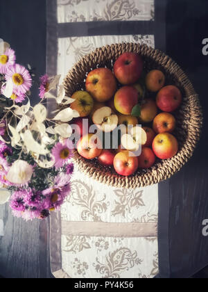 Organische Äpfel in einem Korb. "Astern' und 'lunarias' Herbst Blumen. Saisonale Elemente von oben fotografiert. Stockfoto