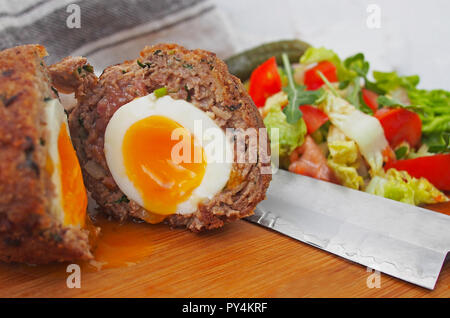 Der traditionelle cotch Ei" auf einer Holzplatte. Scotch Eiern und Salat Stockfoto