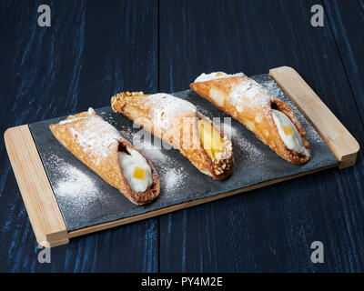 Cannoli Gebäck auf einem Schiefer, ein traditionelles sizilianisches Dessert von u-förmige Schalen der frittierte Teig, mit einem süßen, cremigen Ricotta Füllung Stockfoto