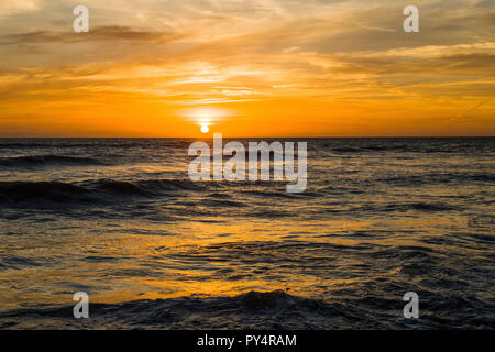 Die Sonne über llantwit Major Strand mit schönen orange Farben über das Meer widerspiegeln, an der Glamorgan Heritage Coast, South Wales Stockfoto