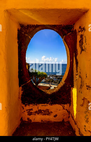 Ein Fenster mit Blick auf den Ozean in farbenfrohem Gelb fort in Funchal - Madeira - Portugal Stockfoto