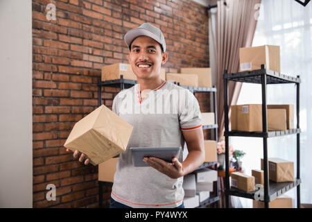 Asiatische junge Mann mit Tablet Pcs und Paket Stockfoto