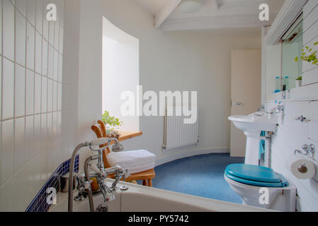 Eine Nahaufnahme von einem modernen Badezimmer mit einer blauen Fußboden und weißen Wänden, Sonnenlicht durch die Fenster kommt und die Aufhellung der Zimmer. Stockfoto