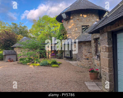Einen weiten Blick Schuß eines luxuriösen Mühle umgewandelt in die Landschaft neben Bäumen und einem Stein Auffahrt. Stockfoto