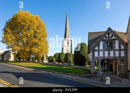 Painswick St Mary's Parish Church und lychgate mit herbstlich gefärbten Bäumen am Nachmittag, Sonnenschein, Painswick, Cotswolds, Gloucestershire, England, Großbritannien Stockfoto
