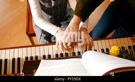Ein kleines Mädchen Klavier spielen auf Musik Lektion. Ein Lehrer ihr zu helfen. Hände Stockfoto