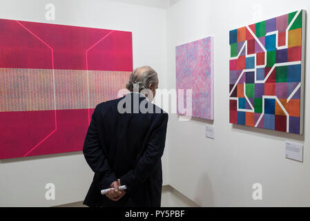 London, Großbritannien. 25. Oktober 2018. Ein Besucher (L, R)' Prism Magenta Grün Gelb", 2015, "Synthese Rosa Blau", 2018 und "Sync", 2016, alle von Colin McCallum. Vorschau von 'Metropole', eine Einzelausstellung von den letzten Gemälde des Künstlers Colin McCallum am Hebel Galerie. Die Ausstellung läuft vom 26. Oktober bis 10. November 2018. Credit: Stephen Chung/Alamy leben Nachrichten Stockfoto