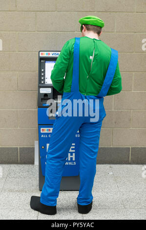 ExCel, London, UK. 26. Oktober, 2018. Drei Tag MCM Comic Con, Comic und Cosplay fest, öffnet sich bei ExCel mit frühen Ankünften in Rollenspiel Kostüm. Super Mario Luigi an einem Geldautomaten. Credit: Malcolm Park/Alamy Leben Nachrichten. Stockfoto