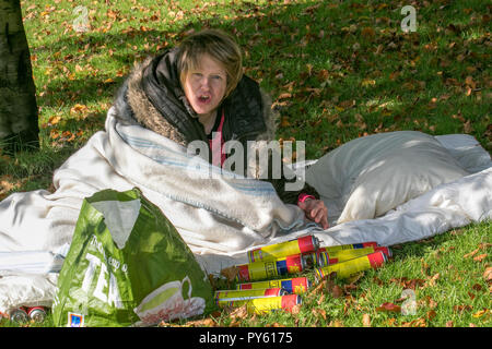 Rauer Schläfer mit Butan-Gaskanistern. Kelly schläft rau auf nassem Gras neben mehreren Dosen ausrangierten Butanleichterbrennstoffs. Stockfoto