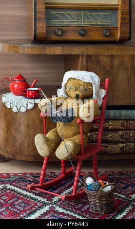 Teddybär oma Stricken in einem Schaukelstuhl in einem vintage Innenraum Stockfoto