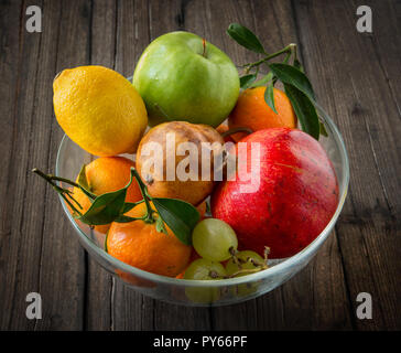 Glas Schale mit frischem Obst auf braune Holztisch Stockfoto