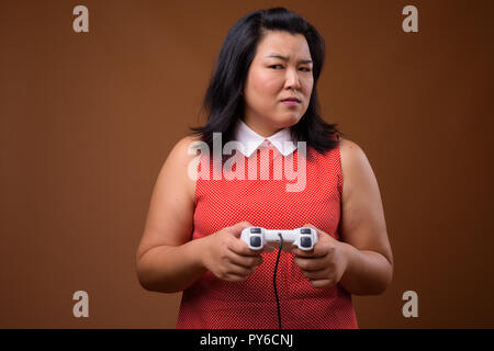 Schöne Übergewicht asiatische Frau spielen Videospiele mit Game Controller Stockfoto
