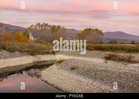 Grün und Orange im Herbst Blätter an der Baumgrenze und purple sky Reflexion im Wasser Stockfoto