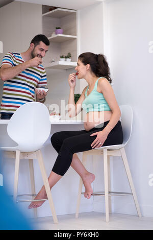 Junge schwangere Paare essen Erdbeeren in Küche, Lifestyle gesunde Schwangerschaft glückliches Leben Konzept Stockfoto