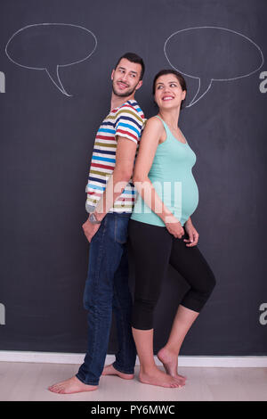 Junge schwangere paar Gedanken über Namen für Ihr ungeborenes Baby und sie schreiben auf eine Schwarze Schiefertafel Stockfoto