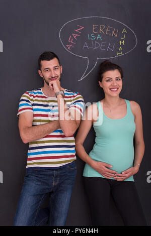 Junge schwangere paar Gedanken über Namen für Ihr ungeborenes Baby und sie schreiben auf eine Schwarze Schiefertafel Stockfoto