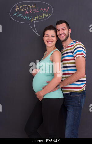 Junge schwangere paar Gedanken über Namen für Ihr ungeborenes Baby und sie schreiben auf eine Schwarze Schiefertafel Stockfoto