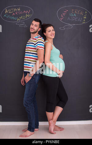 Junge schwangere paar Gedanken über Namen für Ihr ungeborenes Baby und sie schreiben auf eine Schwarze Schiefertafel Stockfoto
