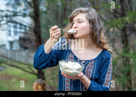 Junge Frau, Draußen, Draußen, holding Glas Schüssel voll mit hausgemachten, Raw vegan Vanilleeis, Schaufeln Schaufel mit Löffel in der einen Hand, Essen, tastin Stockfoto