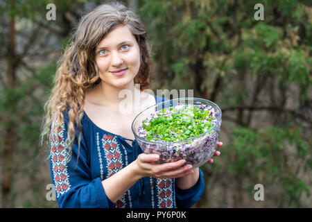 Junge Frau, Draußen, Draußen, holding Glas Schüssel voll mit hausgemachten rot, lila Krautsalat mit grünen Zwiebeln, Frühlingszwiebeln
