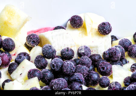 Makro Nahaufnahme von Obstsalat in Schüssel mit eingefrorenen Blaubeeren, Heidelbeeren, Blaubeeren, Bananen, Äpfel Stockfoto