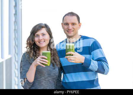 Junges Paar, Frau, Mann, Mann, Frau, Draußen, Draußen, trinken ein Glas grün gesund Smoothie, umarmt, umarmt Stockfoto