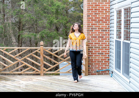 Eine junge Frau außerhalb wandern, im Freien barfuß auf Holz- Haus, Home Deck, bis Suchen, Eigenheimbesitzer im Hinterhof, Vorplatz Stockfoto