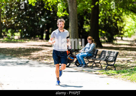 Atlanta, USA - 20. April 2018: Mann laufen Joggen auf Sonnig hellen Tag in Shorts Musik in Piedmont Park trail Pfad Straße in Georgien Stadt i Stockfoto