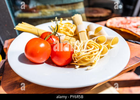 Nahaufnahme von frischen roten Tomaten auf Platte mit Raw trockene Teigwaren Nudeln auf weiße Platte shop shop Anzeige außerhalb Restaurant Street Stockfoto