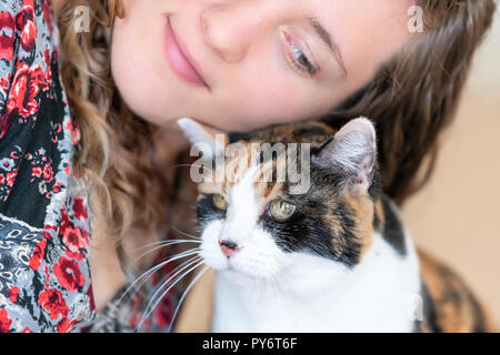 Junge Frau Verklebung mit Calico Cat bumping Reiben bunting Köpfe, Freunde Freundschaft Begleiter Haustier glücklich Zuneigung bonding Gesichtsausdruck, cute Ador Stockfoto
