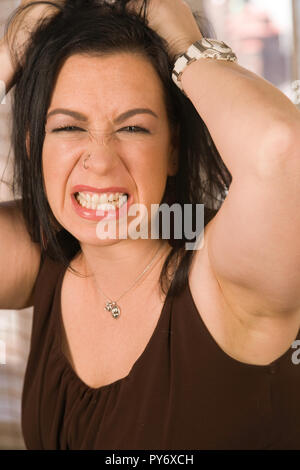 Zornige junge Frau Grütze ihre Zähne und zieht ihre Haare in der Frustration, USA Stockfoto