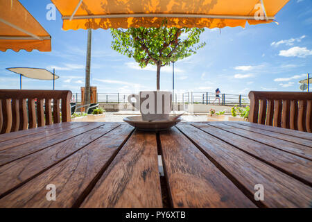 Portugiesische Espresso Tasse oder Bica über Holz- Tabelle. Entspannen Sie auf der Terrasse von Cabanas de Tavira, Algarve, Portugal Stockfoto