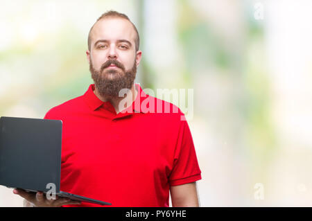 Jungen kaukasischen Mann mit Computer Laptop über isolierte Hintergrund mit einem selbstbewussten Ausdruck auf Smart Face denken Ernst Stockfoto