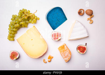 Verschiedene Käse mit Nüssen und Trauben auf dem Tisch. Ansicht von oben Bild von weichen und harten Käse Stockfoto