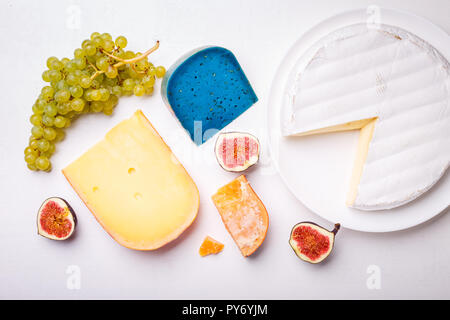 Verschiedene Käse mit Nüssen und Trauben auf dem Tisch. Ansicht von oben Bild von weichen und harten Käse Stockfoto