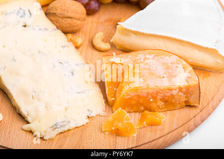 Verschiedene Käse und Nüsse auf dem Tisch. Weichkäse mit Schimmel- und Hartkäse auf dem Schneidebrett Stockfoto