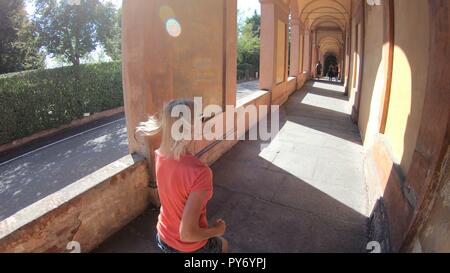 Sportbekleidung Mädchen unter San Luca längste Torbogen in der Welt, die mit dem San Luca Heiligtum der Stadt Bologna in Italien. Stockfoto