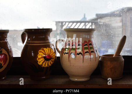 Traditionelle rumänische Töpfen auf einem Holzregal in einem alten Haus, vor einem Fenster in Dobrogea, Rumänien. Stockfoto