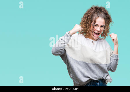 Schöne Brünette lockige Haare junge Mädchen Tragen einer Brille über isolierte Hintergrund sehr glücklich und aufgeregt, Sieger Geste mit erhobenen Armen, smilin Stockfoto