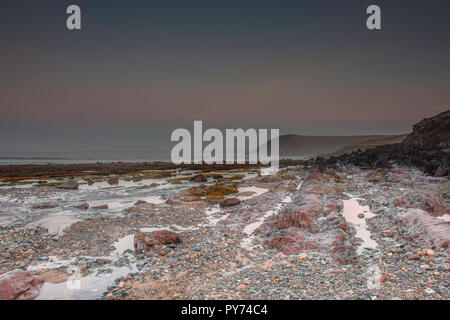 Landschaftsfotografie. Ebbe während der Blauen Stunde am malerischen Felsstrand vor Sonnenaufgang in der Nähe von Tenby, Pembrokeshire, South Wales, UK. langen Belichtungszeit. Natur UK Stockfoto