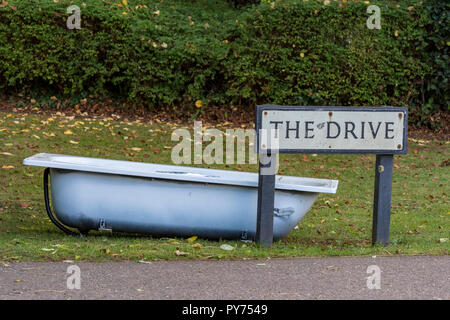 Schuttplatz und eine verlassene Fliegen gespitzt Badewanne neben einem straßenschild am Ende der Straße links oder auf Gras kurz vor. Fliegen kipper Müll. Stockfoto