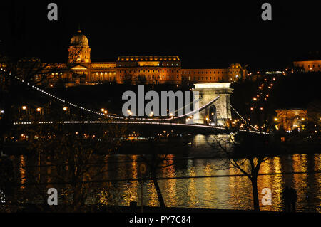 Beleuchtete Széchenyi Kettenbrücke über den Fluss auf dem Hintergrund der Königliche Palast in einer Winternacht. Budapest. Stockfoto