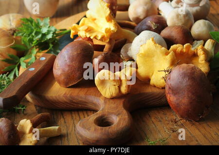 Mischung von Waldpilzen auf Schneidebrett über alten Holztisch Stockfoto