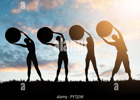 Silhouette von Menschen Trainieren mit Fitness Bälle gegen bewölkter Himmel bei Dämmerung Stockfoto