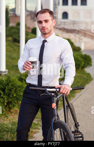 Young Business Mann mit Fahrrad Kaffee trinken von Take-away-Becher Stockfoto