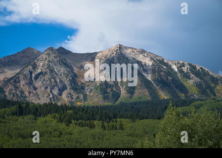 Ein Berg und Bäume. Blauer Himmel mit Wolken und viel Vegetation. Stockfoto